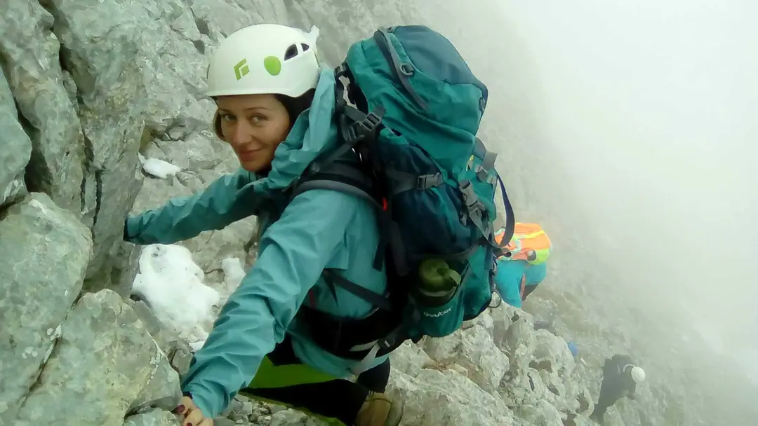 Smiling climber with helmet and backpack on an alpine ridge