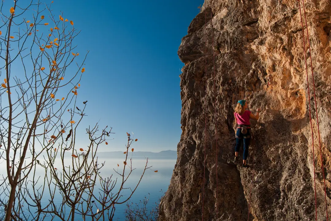 Climber on an orange limestone wall above Lake Ohrid