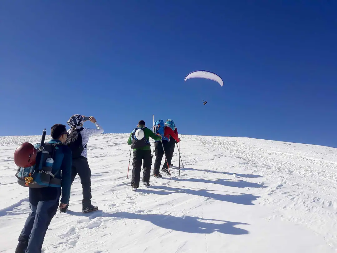 Winter hikers on the snow with a paraglider overhead