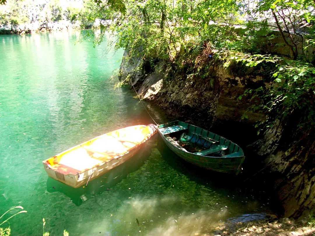 Two boats in clear green water under the cliffs of Matka