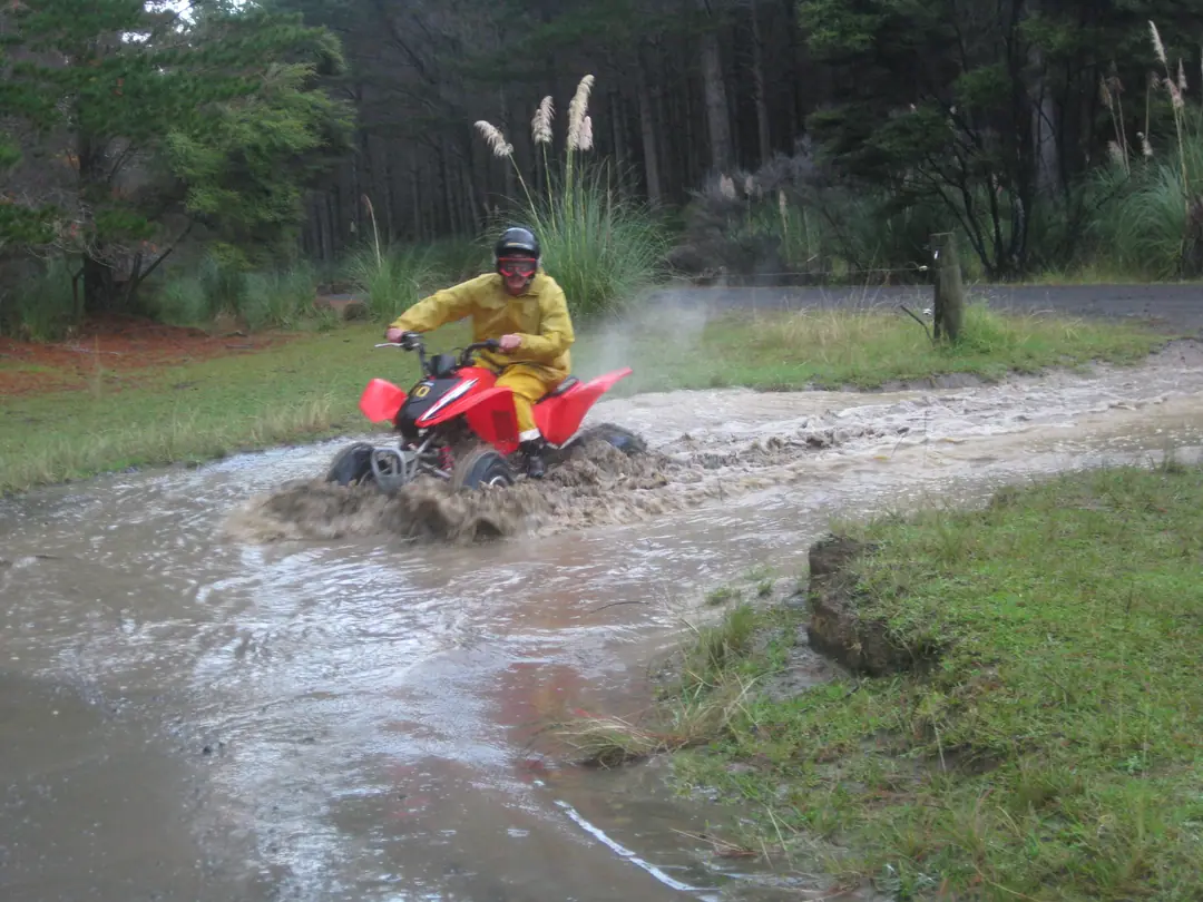 Red quad splashing through a muddy puddle