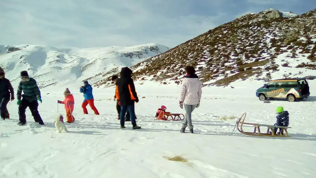 Families sledding in the snow, the 4x4 van parked behind